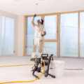Pintor profesional aplicando pintura en cielo interior con bomba airless Wagner ProSpray 4.23 y extensión de pistola.
